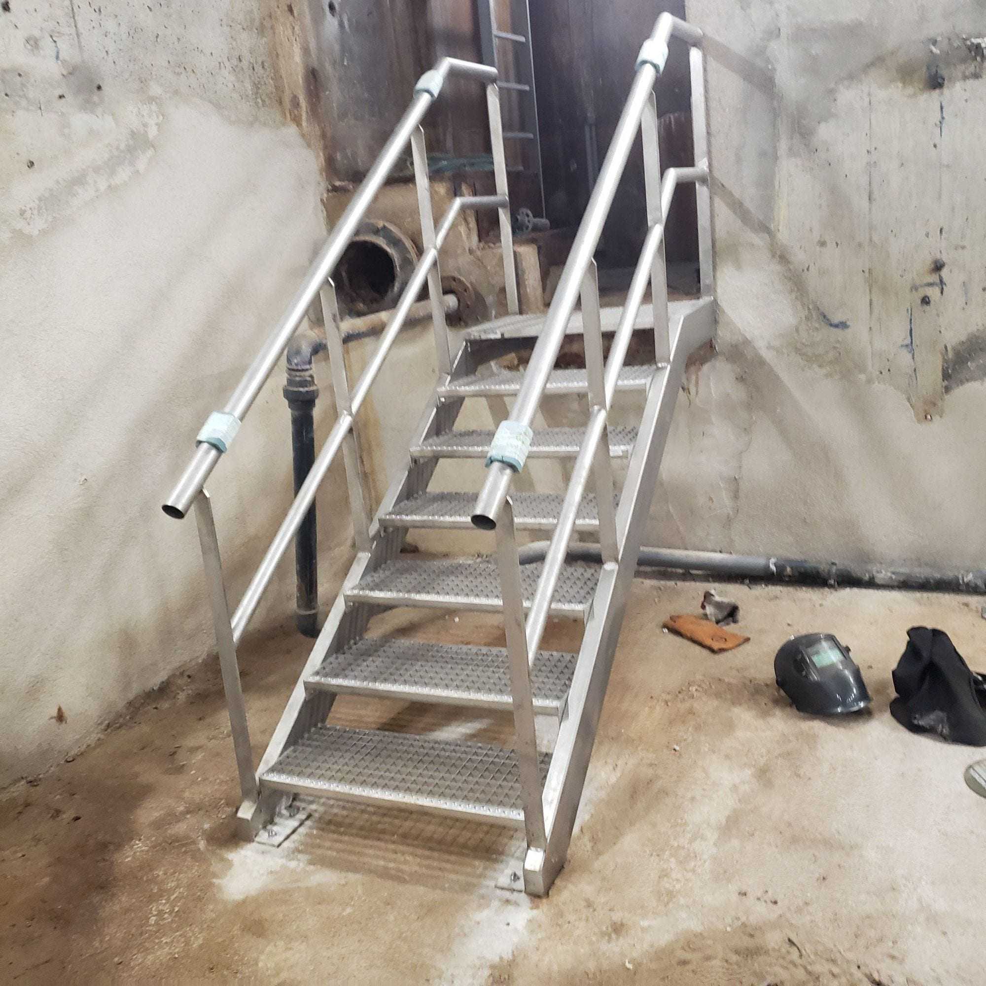 Stainless steel staircase with open-grid steps and tubular handrails