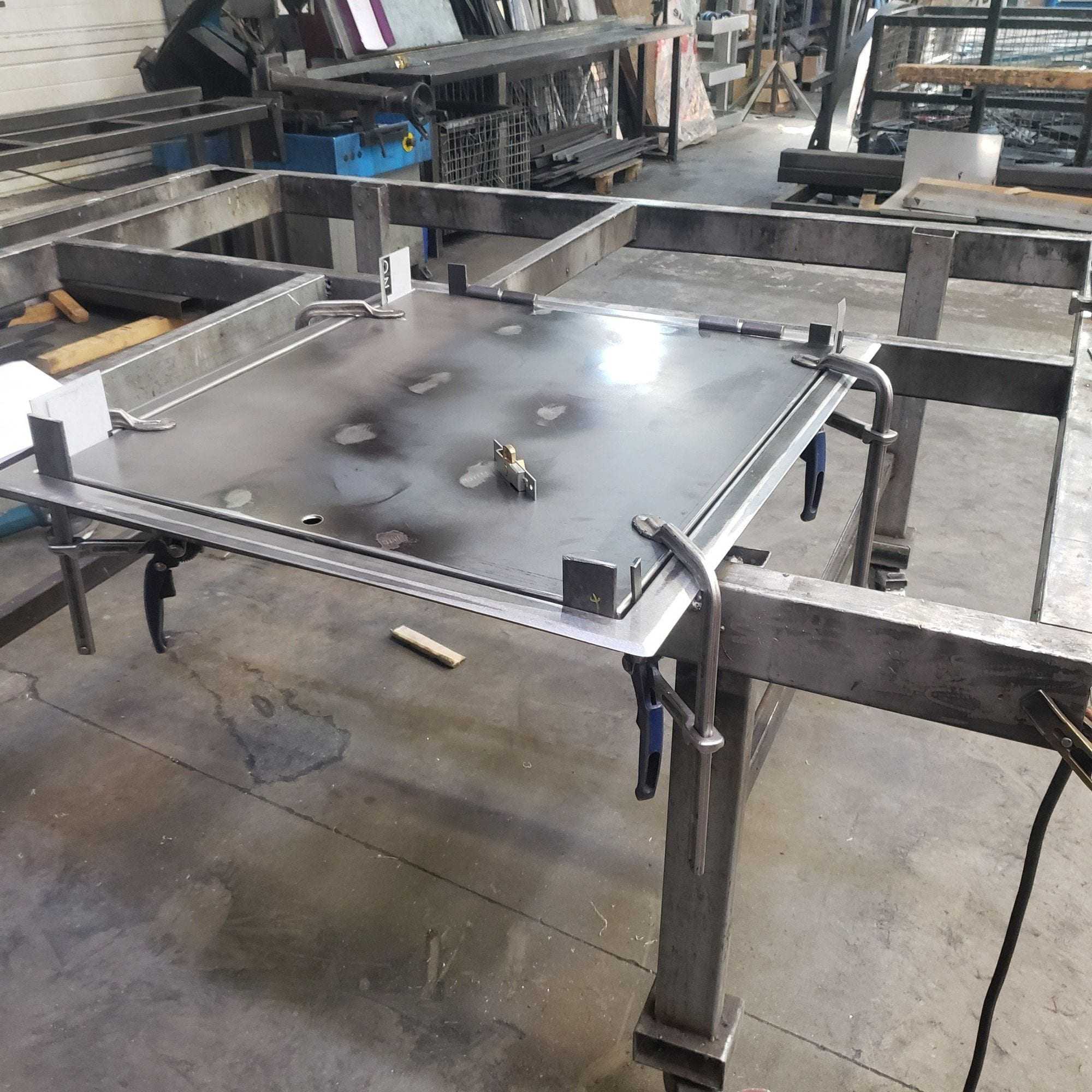 Steel plate held with clamps on a welded frame, in the workshop